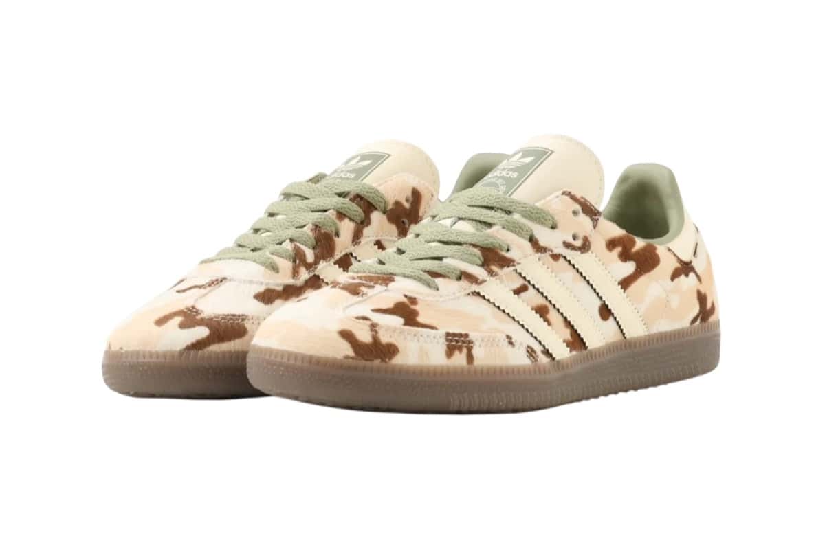 Par de adidas Samba Camo Cow Print visto en diagonal sobre fondo blanco, con upper de pelo en manchas marrones, beige y crema, tres tiras de cuero crema, cordones verde salvia y suela gum oscura